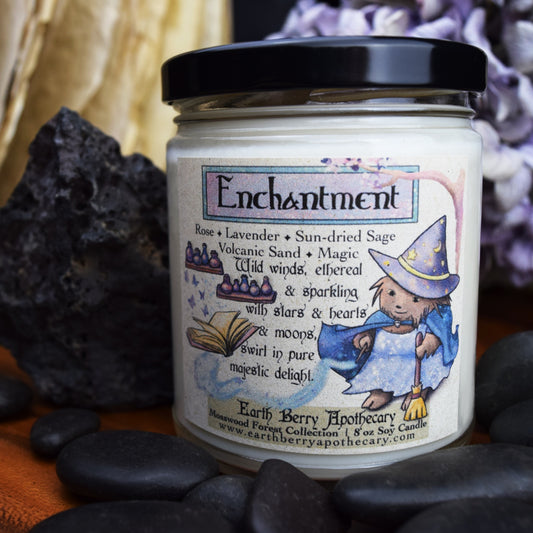 Nature fantasy candle called enchantment. Featuring a hedgehog hedge witch holding a broom, and a wand hat is levitating a book. Magic jars sit on a shelf.