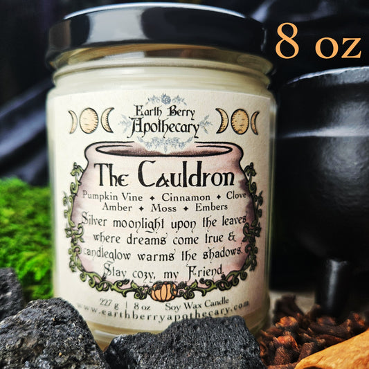 Candle jar labeled 'The Cauldron' from Earth Berry Apothecary with decorative text and imagery.