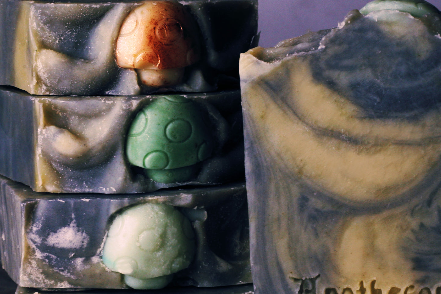 green and black handmade soap scented with patchouli and sandalwood, with mushroom embeds