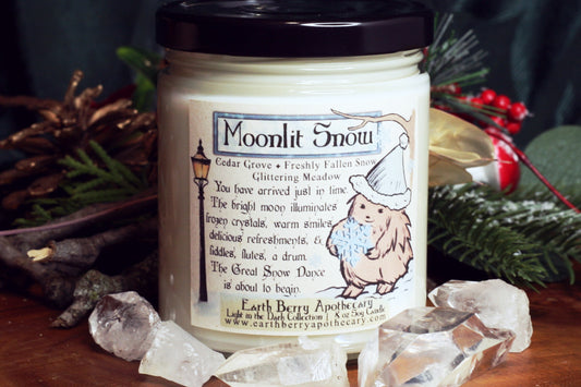 Moonlit snow winter scented soy candle. Pine and cedar with snowy branches. The hedge witch holds a snowflake.