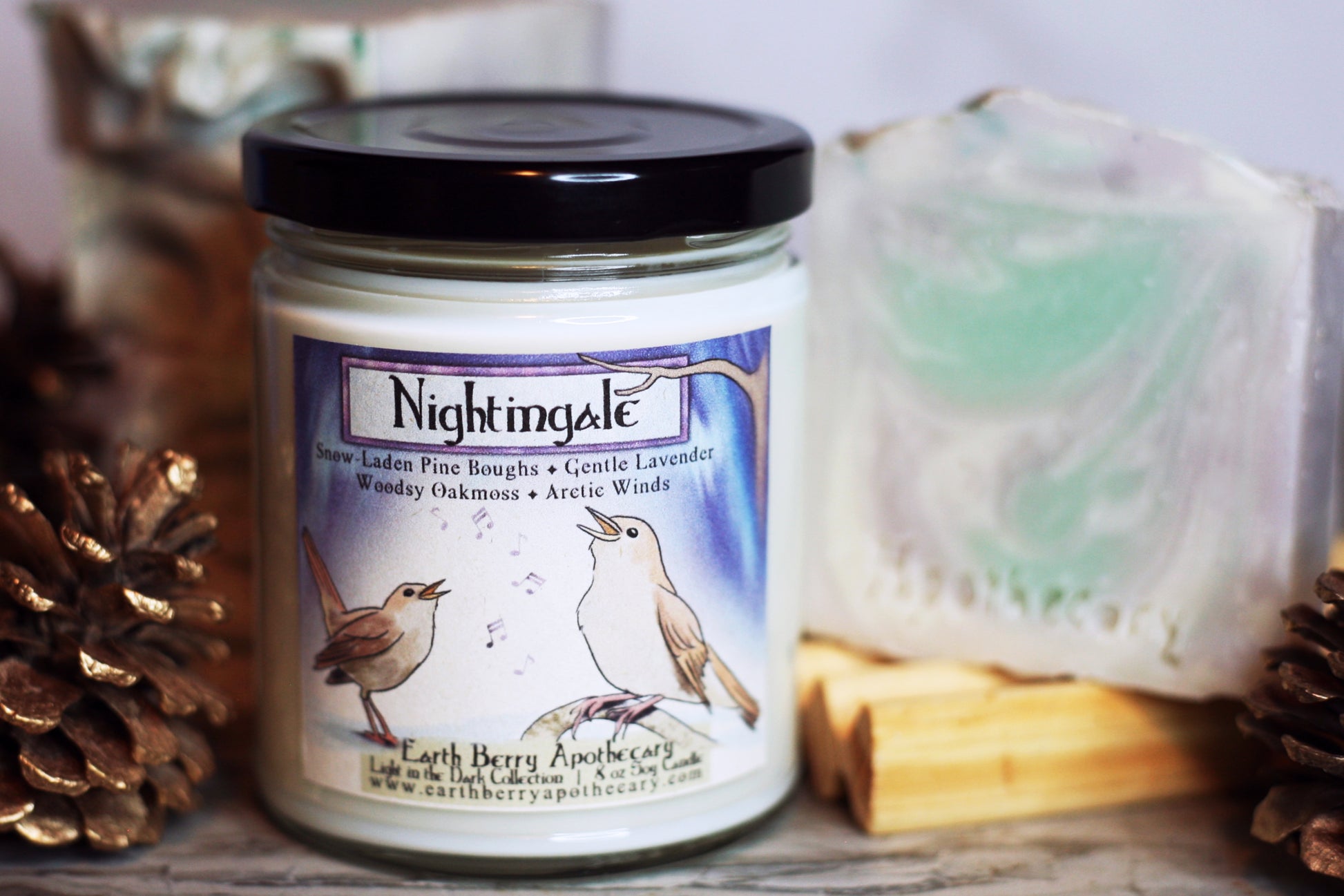 Nightingale handmade soap and soy candle bundle. The scent is pine and lavender. The soap has green, purple, and white swirls. The candle has two birds singing in front of the northern lights
