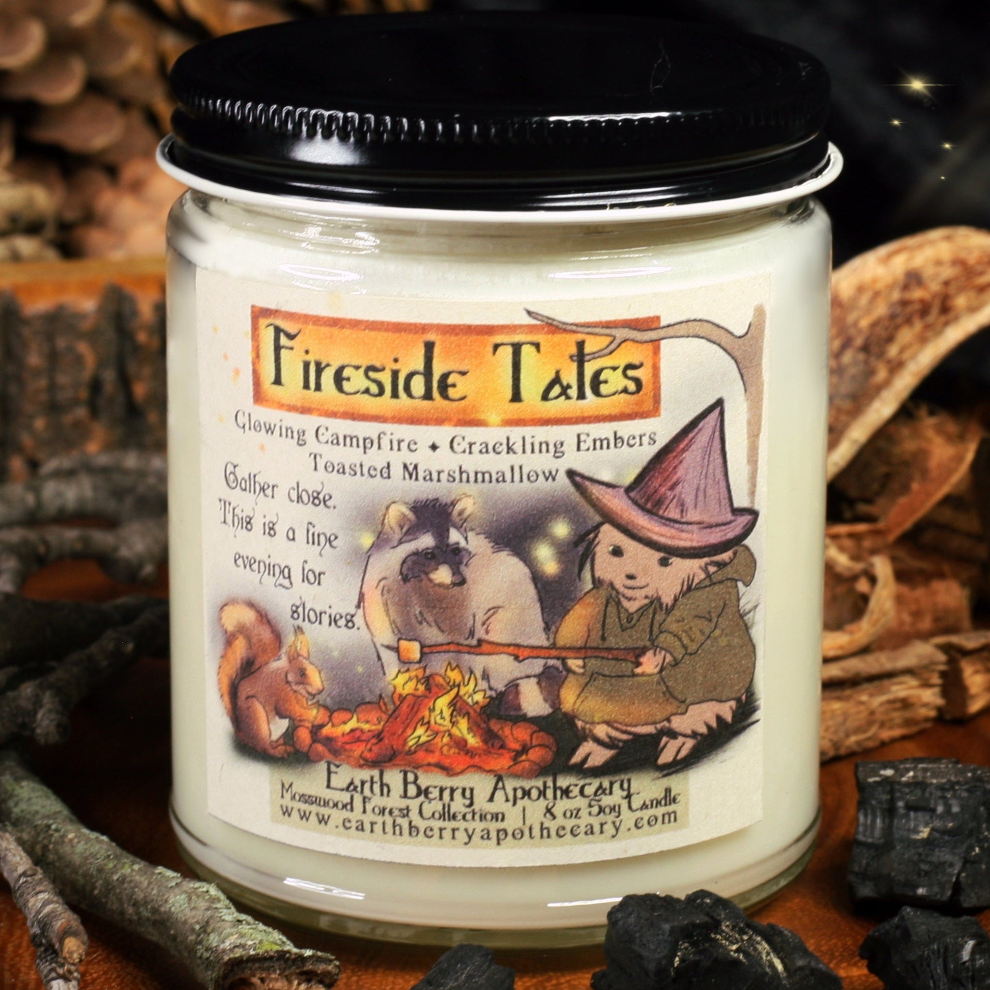 Fireside tales soy candle scented with campfire embers and toasted marshmallows. The hedgewitch sits in front of a campfire, tossing a marshmallow, while a raccoon and squirrel tell stories.