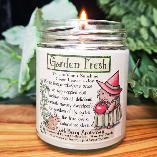 Lit candle in a jar labeled 'Garden Fresh' with a hedgehog in a witch hat illustration. The scent is tomato vine.
