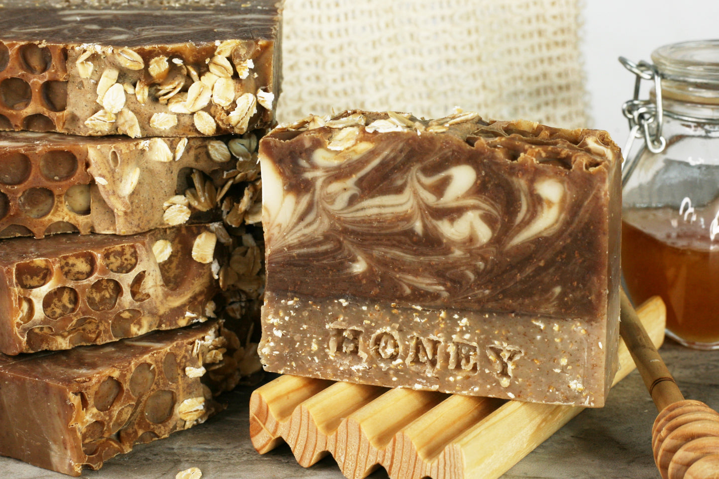 Honey is stamped in a layer of exfoliating oatmeal, with a brown and white swirled layer above this spiced honey scented soap. The top is sprinkled with oats with a textured honeycomb imprint.